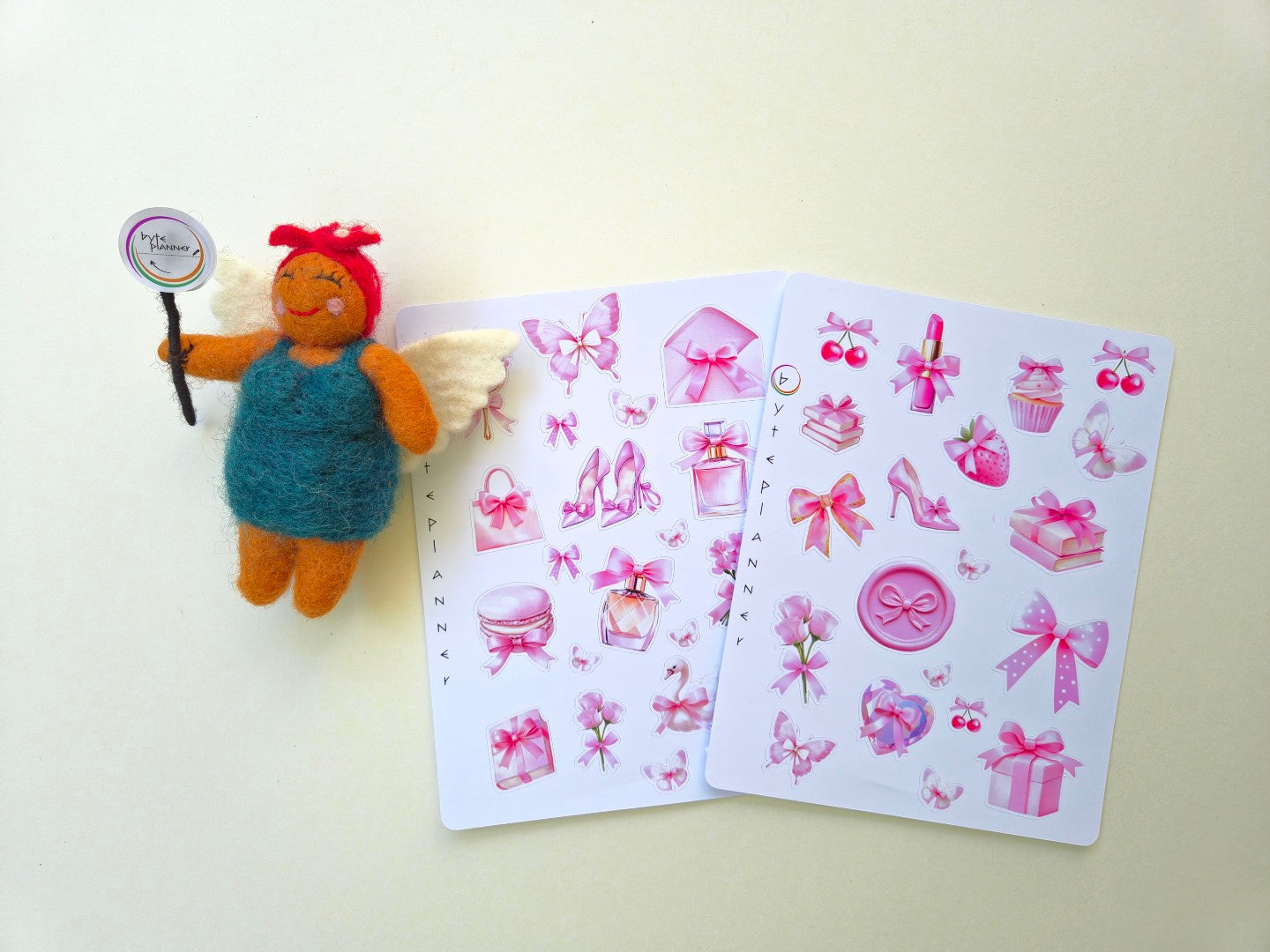 Zwei Stickerbögen im Format 13 × 17 cm mit romantischen pastellrosa Motiven (Schleifen, Parfumflakon, Geschenkboxen, Cupcake, Erdbeere, Kirschen, Blumen und Schmetterlinge) auf weißem Hintergrund