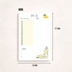 Minimalistischer Notizblock ‚Mein Tag‘ mit Zitronenmotiv, Tagesplan von 6 bis 23 Uhr, Datumsfeld und drei Prioritäten, fotografiert neben einem goldfarbenen Stift auf hellem Hintergrund.