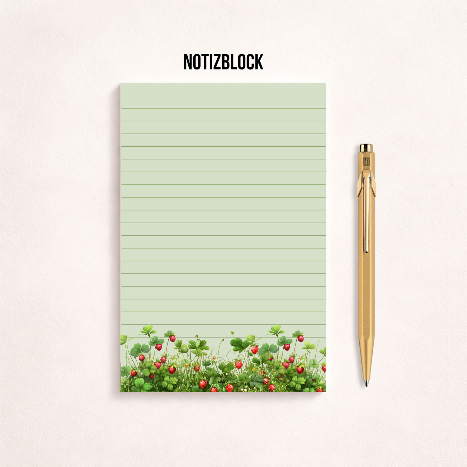 Liniertes Notizpapier im Hochformat mit grün-rosa Erdbeerwiesen-Motiv am unteren Rand, fotografiert auf dunkelgrauem Hintergrund. Links daneben liegt ein transparenter Stift parallel zum Block. Cleanes, minimalistisches Flatlay mit viel freiem Raum