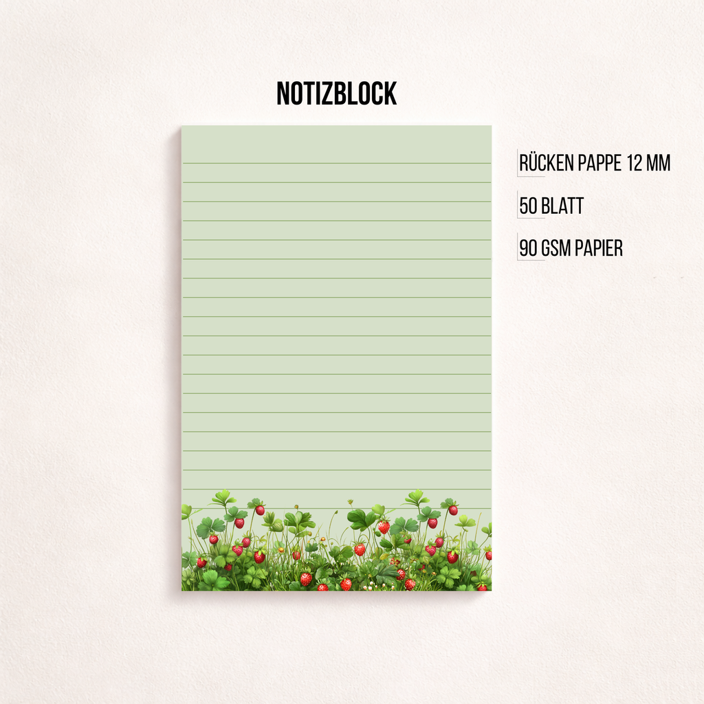 Liniertes Notizpapier im Hochformat mit grün-rosa Erdbeerwiesen-Motiv am unteren Rand, fotografiert auf dunkelgrauem Hintergrund. Links daneben liegt ein transparenter Stift parallel zum Block. Cleanes, minimalistisches Flatlay mit viel freiem Raum