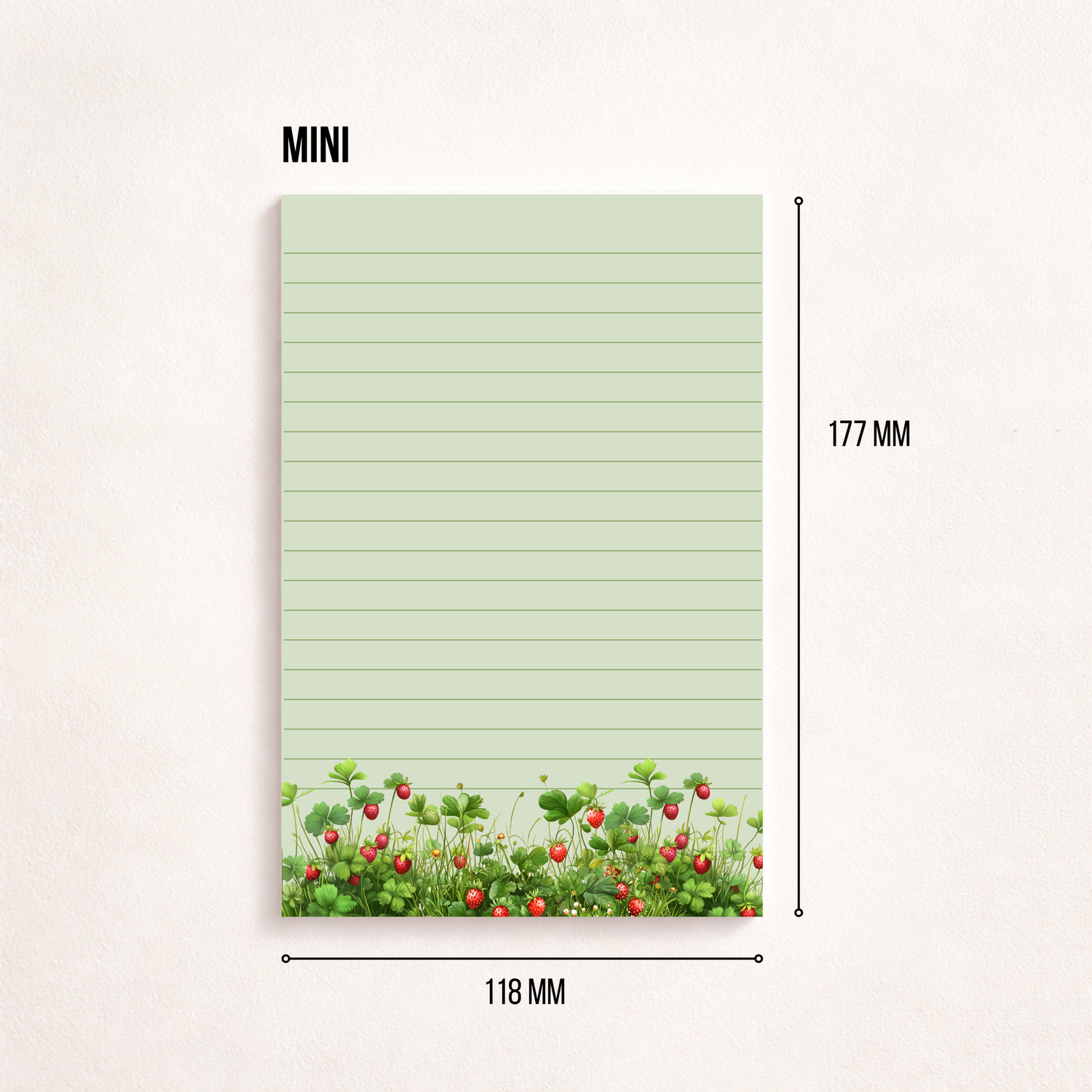 Liniertes Notizpapier im Hochformat mit grün-rosa Erdbeerwiesen-Motiv am unteren Rand, fotografiert auf dunkelgrauem Hintergrund. Links daneben liegt ein transparenter Stift parallel zum Block. Cleanes, minimalistisches Flatlay mit viel freiem Raum